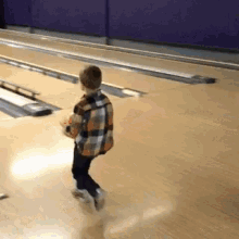 a young boy is playing bowling on a bowling alley
