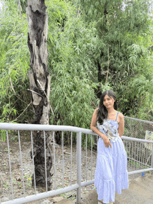 a woman in a white dress stands next to a tree