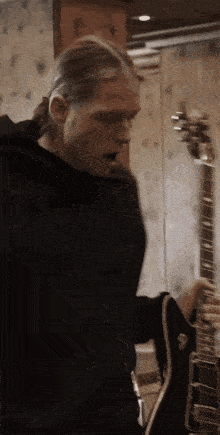 a man in a black hoodie plays a guitar