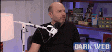 a man in a black shirt is sitting in front of a microphone with the words dark web on the bottom right