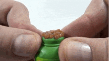 a person is holding a green bag of gold coins between their fingers .