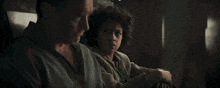 a man and a boy are sitting next to each other in a dark room and looking at each other .