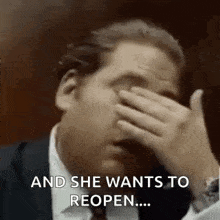 a man in a suit and tie is covering his face with his hand and says `` and she wants to reopen ... ''