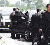 a man in a suit carrying a briefcase is walking towards a car