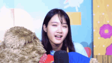 a girl with a teddy bear behind her looks at the camera