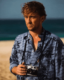 a man wearing a blue shirt is holding a camera