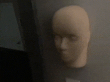a close up of a mannequin head against a dark wall