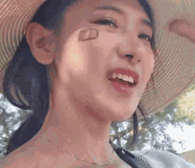 a woman wearing a straw hat and a necklace is smiling .