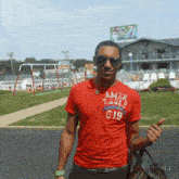 a man wearing a red american eagle shirt stands in front of a playground