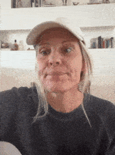 a woman wearing a baseball cap and a black shirt looks at the camera