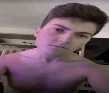 a shirtless young man is taking a selfie with a purple background