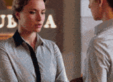 a man and a woman are looking at each other in front of a sign that says jba