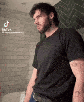 a man with a tattoo on his arm is standing in front of a toilet with a tiktok watermark