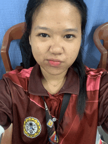 a woman taking a selfie wearing a maroon shirt with the university of the philippines emblem on it