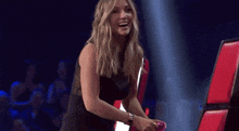 a woman in a black dress is dancing in front of a red and white sign