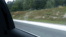 a view of a road from a car window with a fence in the background