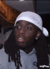 a man with dreadlocks is wearing a white bandana