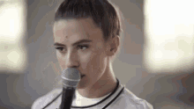 a woman is singing into a microphone while wearing a white shirt .