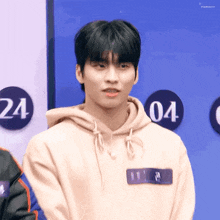 a young man wearing a hoodie is standing in front of a blue wall with numbers on it .