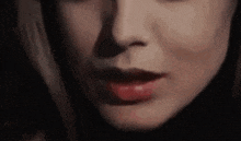 a close up of a woman 's face with red lips and a black background .