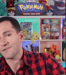 a man in a plaid shirt is sitting in front of a shelf filled with pokemon toys .