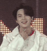 a young man wearing a white jacket and a red shirt is smiling for the camera