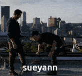 two men standing on a roof with the word sueyann on the bottom right