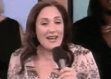 a woman is holding a microphone and smiling while talking into it .