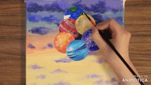 a person is painting balloons on a canvas with the words made in animatica visible