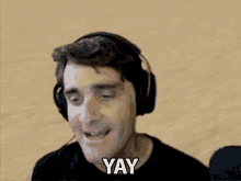 a man wearing headphones is making a face and saying yay .
