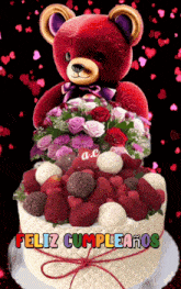 a teddy bear sits on top of a cake with the words feliz cumpleanos written on it
