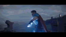 a man in a cape is holding a lightning bolt in his hands .