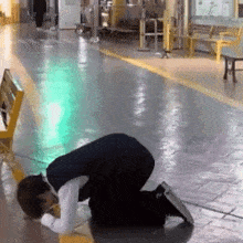 a man is kneeling down on the ground in a hallway
