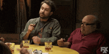 two men are sitting at a table with glasses of whiskey and a fx logo in the corner