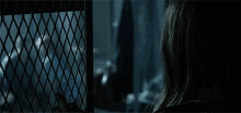 a woman is behind a metal fence looking out