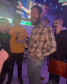 a man in a plaid shirt is holding a beer bottle