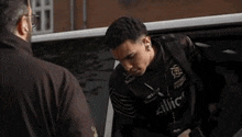 a man is getting out of a car with a man standing behind him .
