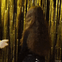 a woman with long hair is standing in front of a gold curtain that says ritualyas on the bottom