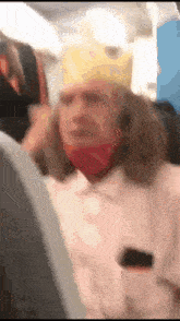 a man wearing a crown and a mask is sitting on a plane