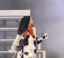 a woman in a cow print outfit is dancing on stage .