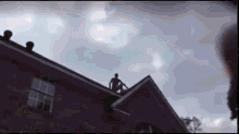 a man is sitting on the roof of a house .