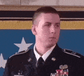 a man in a military uniform stands in front of a flag .