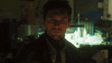 a man is smiling in a dark room with a light shining on his face