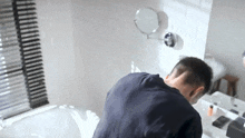 a man is washing his face in a bathroom sink .