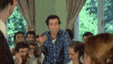 a man in a plaid shirt stands in front of a group of people