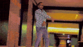 a man in a green and white shirt is standing in a hallway with his arms crossed