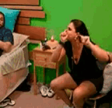 a man is laying on a bed next to a woman who is sitting on a chair