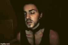 a man with a beard wearing a choker and a black tank top
