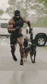 a shirtless man is running with two dogs and a tiktok watermark in the corner