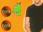 a man in a black shirt is standing in front of a pause button and a green monster .